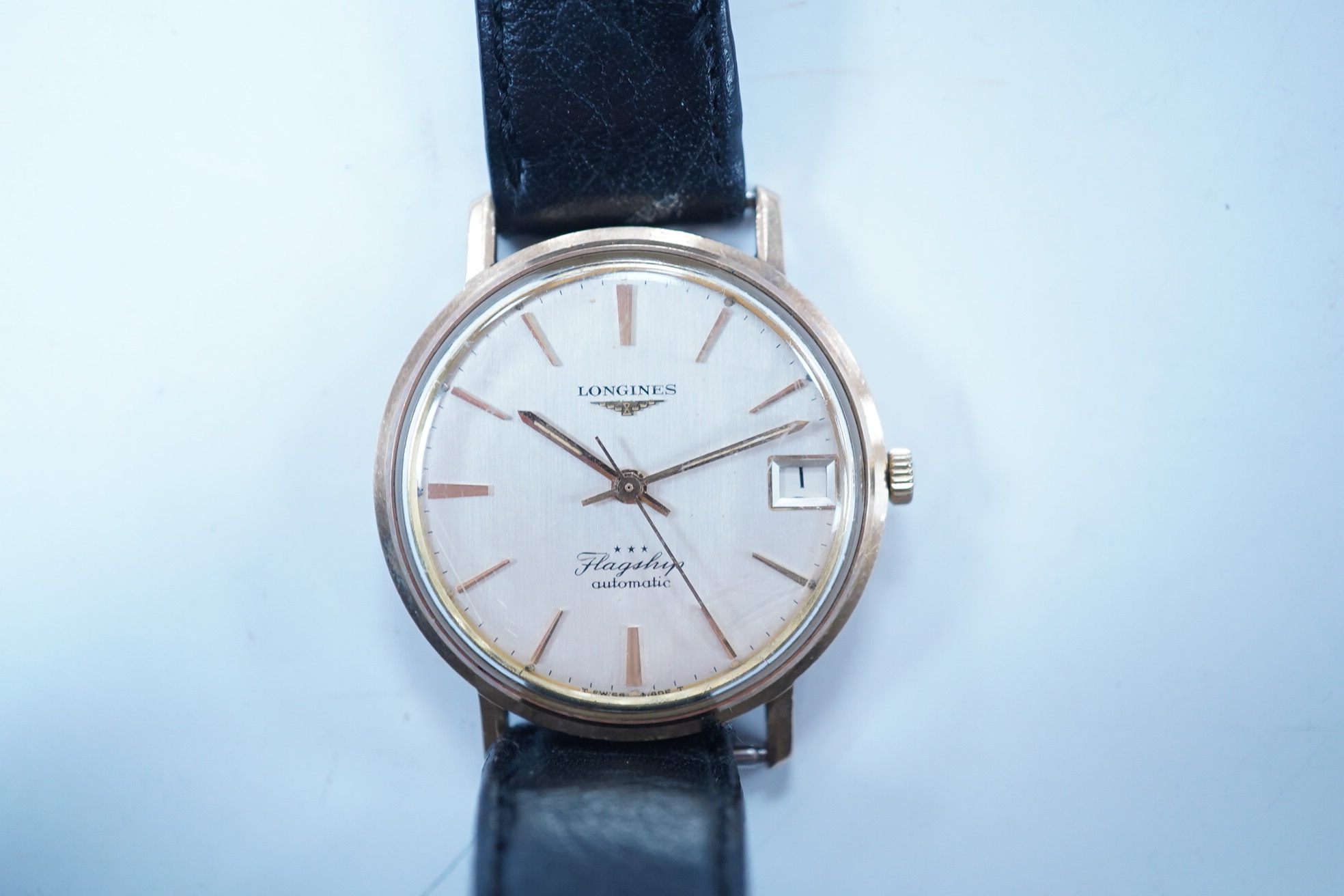 A gentleman's 9ct gold Longines Flagship automatic wrist watch, with baton numerals and date aperture, case diameter 35mm, on an associated leather strap. Condition - poor to fair